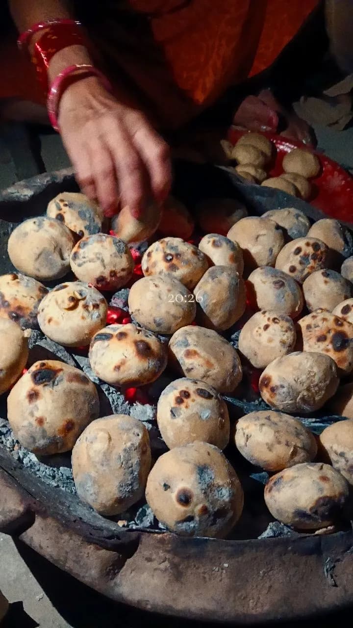 Baati roasting on coals, turned by hand
