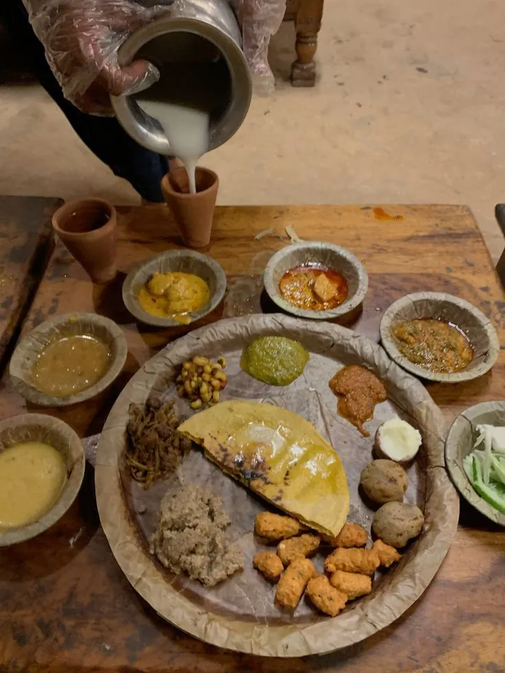 Buttermilk being poured beside a Rajasthani thali
