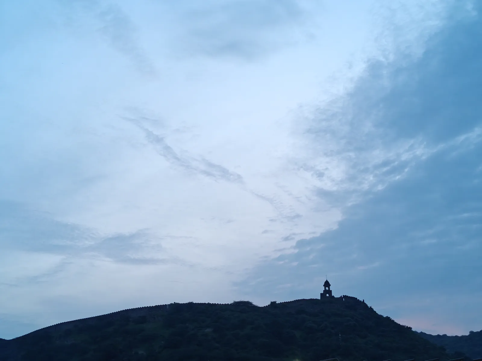 Fortification wall and watchtower on an Aravalli ridge at dusk